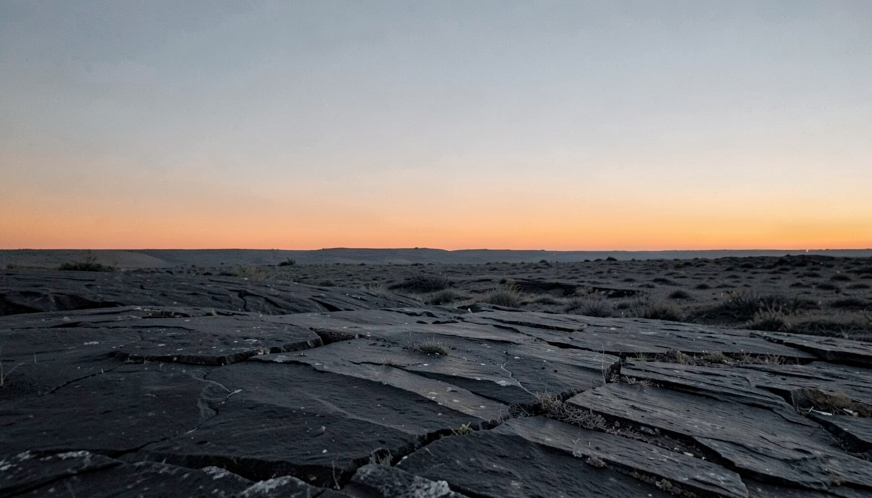 Wide, atmospheric slate-and-charcoal landscape with a soft orange horizon line, used as a background for the blog posts teaser.